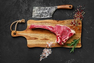 Top view of raw prime ribeye steak on wooden cutting board