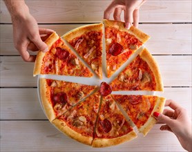 Close-up of people hands taking slices of pizza. Sharing food. Group of friends having pizza together