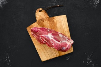 Overhead view of raw lamb rump on wooden cutting board