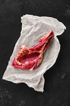 Top view of beef ribeye steak bone-in on wrapping paper