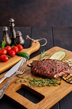 Beef steak and zucchini served with fresh tomato cherry and basil on wooden cutting board