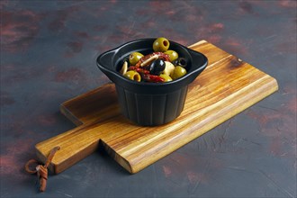 Black and green olives in Spanish on wooden plate