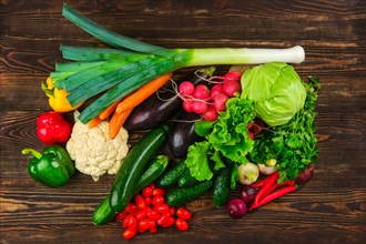 Overhead view of assortment of fresh vegetables on dark wooden background