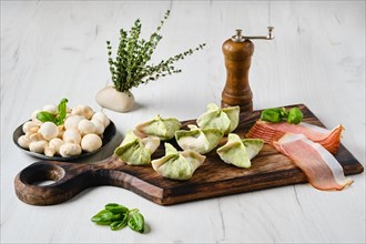 Dumplings stuffed with smoked ham and mushrooms on wooden serving board