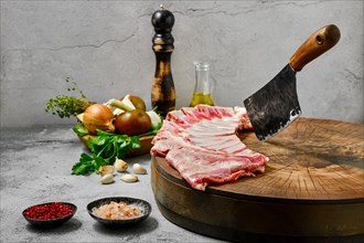 Uncooked lamb flap ribs with ingredients on wooden log