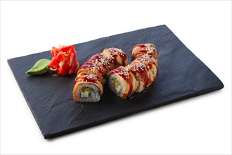 Portion of unagi roll with garnish isolated on white