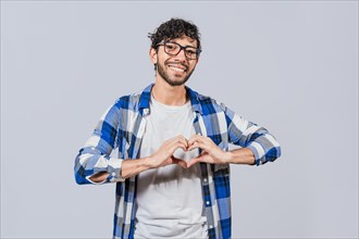 Teenage guy making heart shape with hands isolated. Happy man making heart shape with hands isolated. Person putting hands together in a heart shape