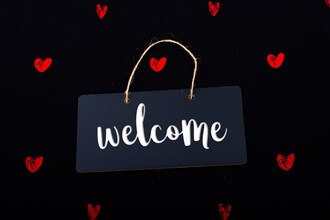 Welcome wording on black notice board with red hearts around
