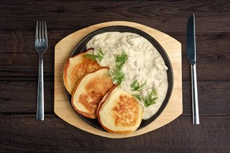 Flapjack with mushroom sauce on wooden plate. Top view