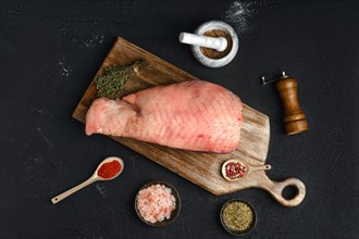 Top view of raw half of turkey breast with bone and skin on dark background