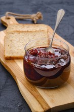 Transparent pot with cherry jam and toast bread