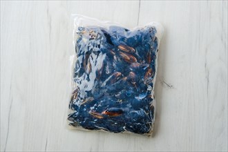 Cooked frozen mussels meat in vacuum packaging on wooden table