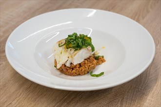 Fried white fish fillet with quinoa porridge on wooden table