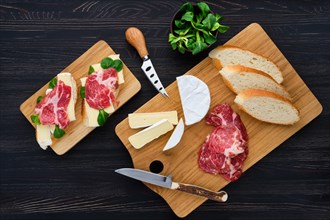 Overhead view of camembert sandwich with smoked bacon on dark wooden table