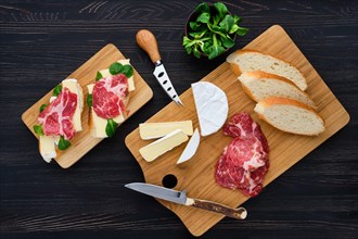 Overhead view of camembert sandwich with smoked bacon on dark wooden table