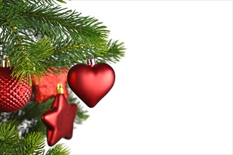 Red heart shaped Christmas bauble on decorated Christmas tree on side of white background with copy space