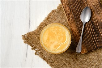 Top view of pot with honey and spoon on wooden serving board