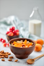Muesli with apricots and almonds on white wooden table
