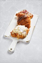 Various croissants on white serving board on marble background