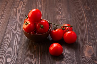 Branch of fresh tomatoes on wooden table