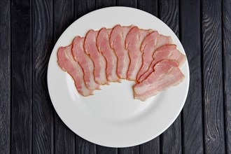Top view of plate with slices of fresh bacon