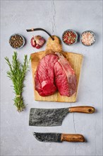 Overhead view of raw fresh deer boneless ham with spice and herb over concrete background