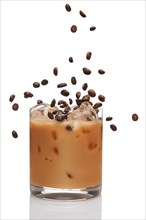 Coffee beans falling into cocktail with Irish creme liqueur in a glass full of ice