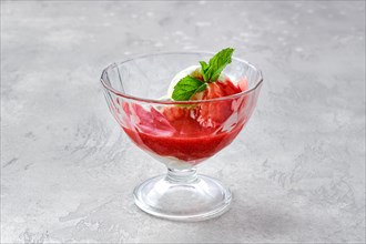 Ice cream with strawberry jam in a glass bowl