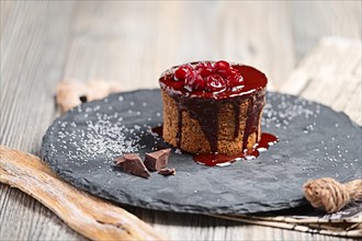 Cake with cherry and chocolate syrup on wooden table
