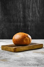 Fresh baked round bun on wooden cutting board
