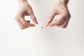 Person s hand breaking cigarette white background