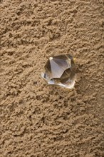 A transparent diamond on a sand background on display