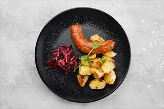 Fried sausage with slices of boiled potatoes fried in oil and marinated beetroot