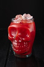 Cocktail bloody Mary in skull cup on dark wooden background