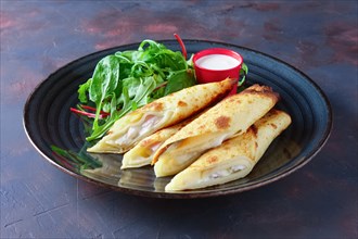 Thin pancakes stuffed with ham and melted cheese served with spinach