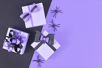 Purple and black Halloween flat lay with paper gift boxes with bows and spiders with empty copy space
