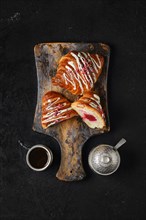 Top view of fresh croissant with raspberry filling on wooden serving board