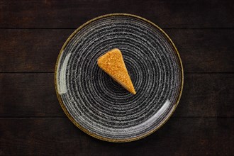 Top view of plate with piece of honey cake on wooden background