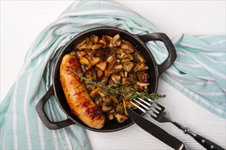 Cast-iron pan with fried sausage and mushrooms