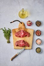 Overhead view of raw fresh deer backstrap with spice and herb over concrete background