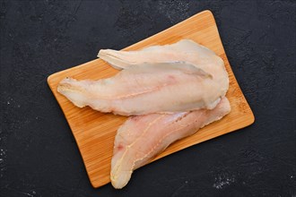 Top view of raw fresh haddock fillet on wooden cutting board