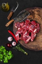 Overhead view of chopping fresh beef meat for goulash or stew on wooden chopping stump