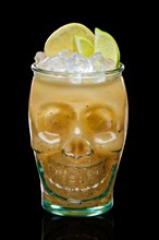 Halloween feijoa cocktail with slices of lime and lemon in skull glass isolated on black