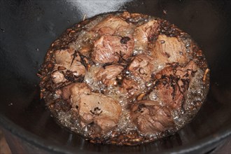 Meat and onions in cauldron. The making of pilaf