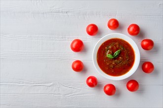 Top view of wooden table with plate with gazpacho and tomato cherry