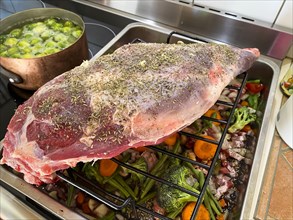 Raw leg of lamb in a roaster with vegetables and spices. Hesse