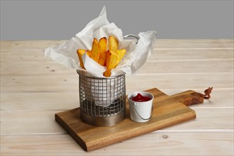 Fried potato in in little metallic basket with ketchup