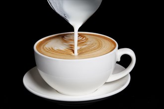 Pouring cream to cappuccino. Big white cup on black background