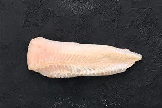 Raw shallow-water hake fillet on black concrete background