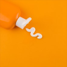 White sunscreen cream coming out orange bottle against orange backdrop. Resolution and high quality beautiful photo